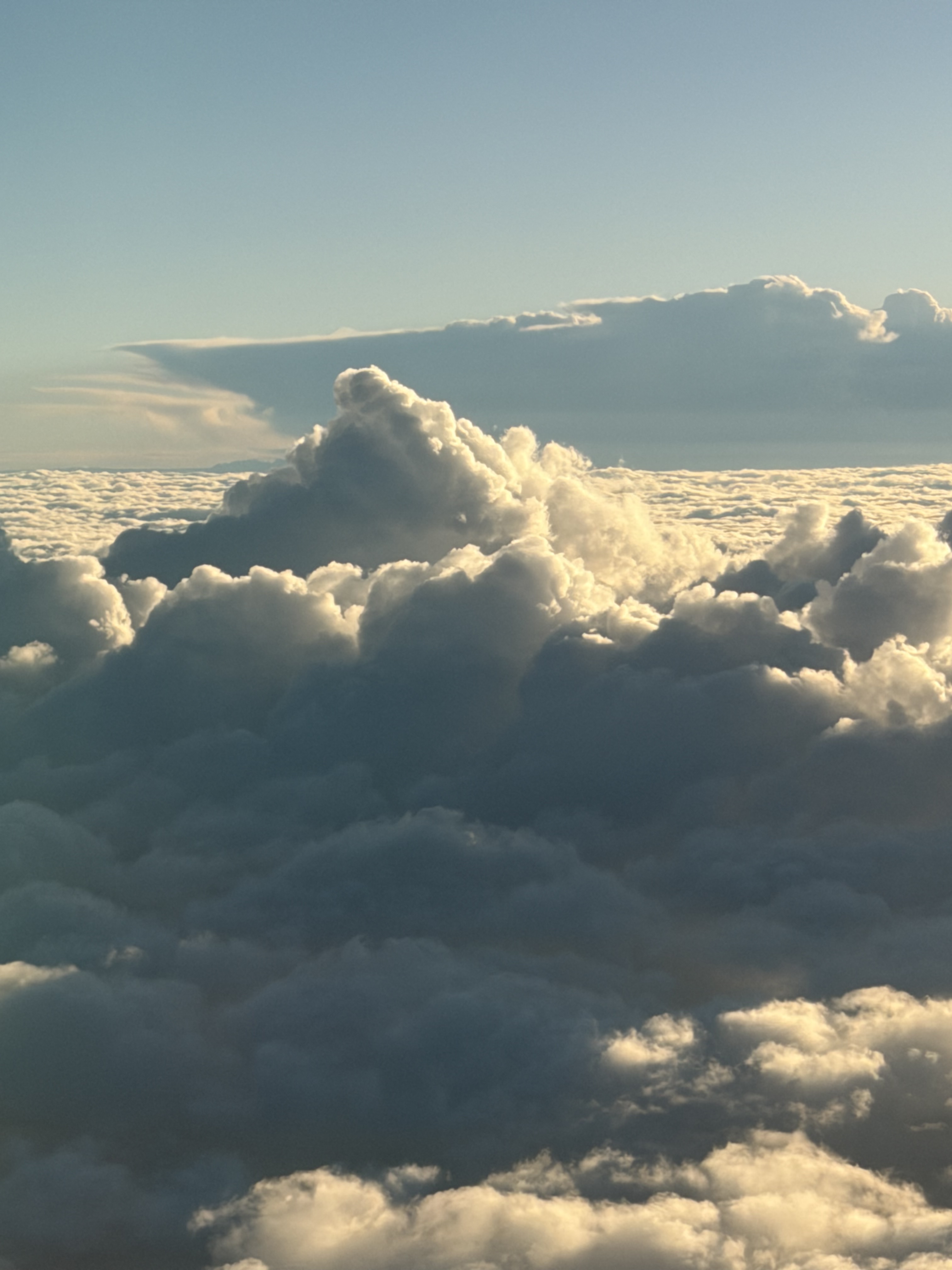 Tall clouds glowing in sunlight beneath a blue sky.
